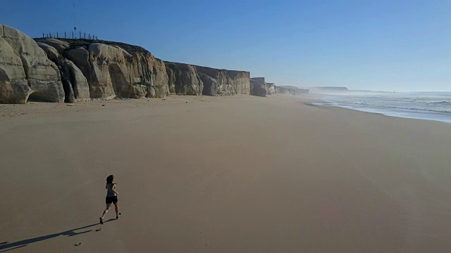 女人沿着海滩慢跑后视图视频下载