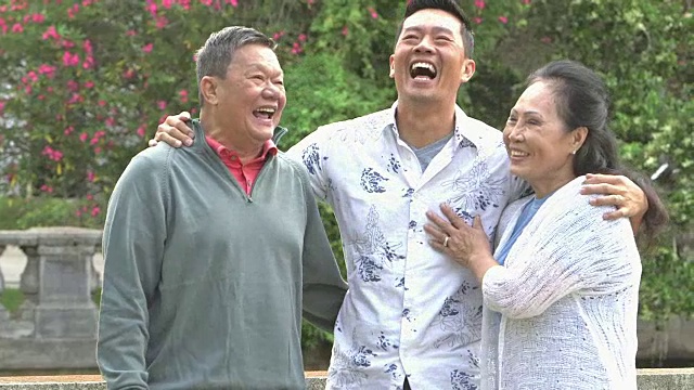 年老的亚洲夫妇和成年的儿子在公园笑视频素材