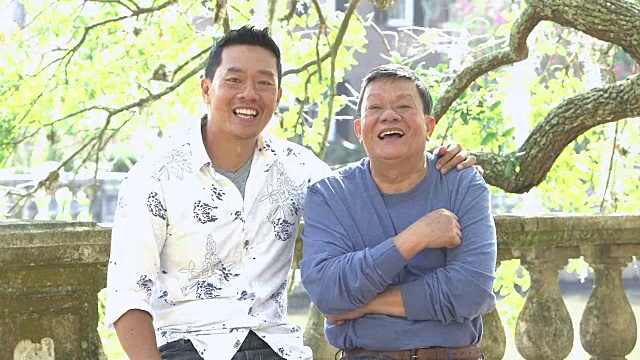 年长的亚洲男人和成年的儿子在公园里谈笑风生视频素材