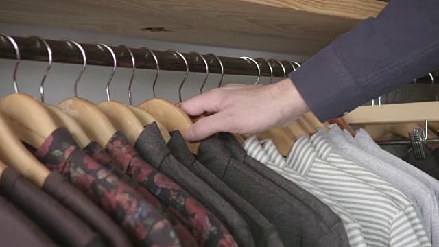 在服装店，零售工人正在整理机库上一排排的衬衫和裤子。视频素材