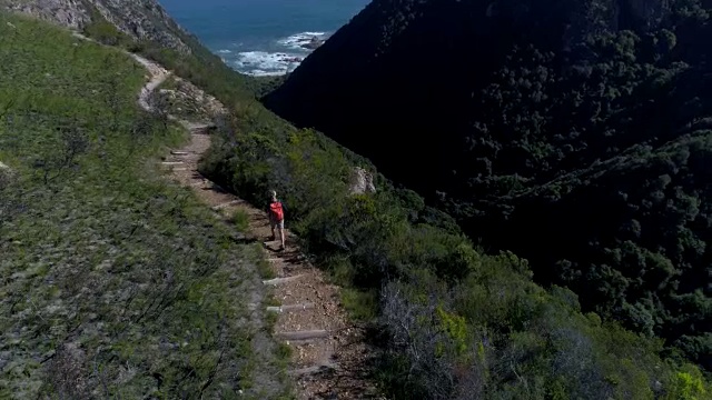 鸟瞰图的年轻女子徒步在山谷的海边，南非视频下载