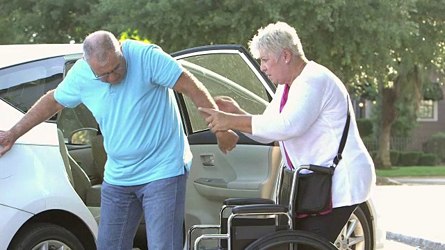 妻子帮助老人从车里坐到轮椅上视频素材