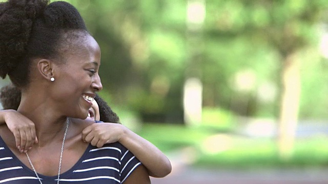 黑人妈妈背着可爱的小女孩在户外视频素材
