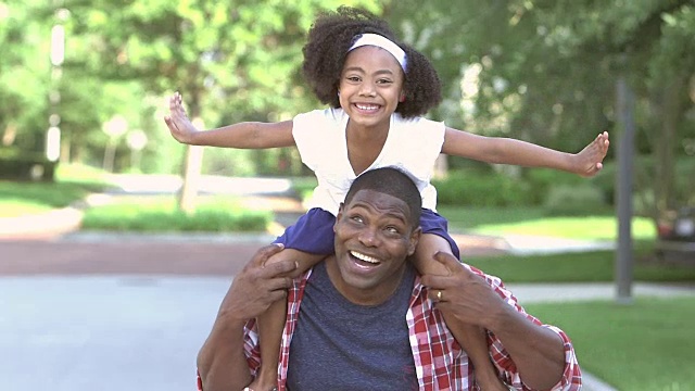 可爱的混血小女孩骑在父亲的肩膀上视频素材