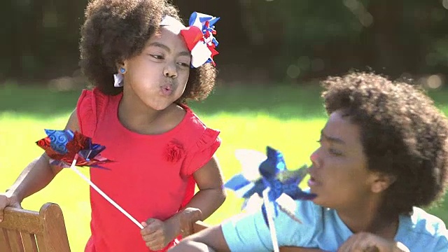 男孩，小妹妹在玩红、白、蓝的风车视频素材