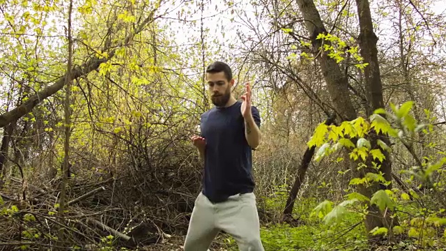 一个年轻人在春天的森林里练习空手道。视频下载