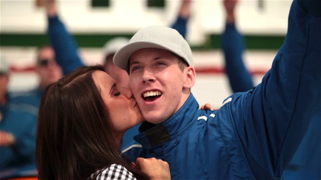 女子亲吻赛车手的脸颊，蓝色车队庆祝胜利视频素材