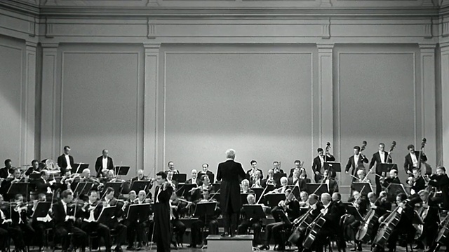 20世纪40年代的宽镜头指挥在舞台上指挥整个管弦乐队的演出视频素材