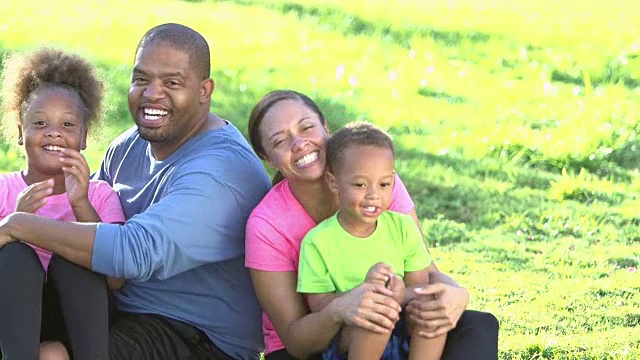 快乐的黑人家庭和两个孩子坐在草地上视频素材