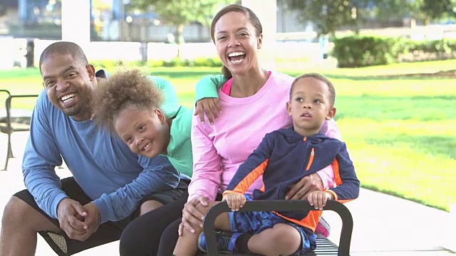 一个快乐的黑人家庭，两个孩子坐在长凳上视频素材