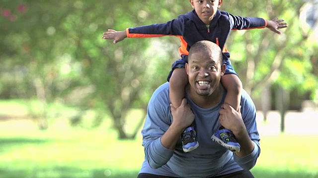 一个非裔美国小男孩在爸爸的肩膀上玩耍视频素材