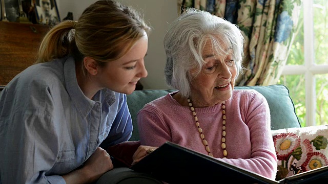 老女人坐在家里和成年孙女一起看相册视频素材