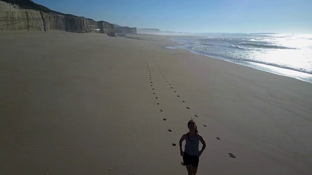 在镜头前的海滩上慢跑的女人视频下载