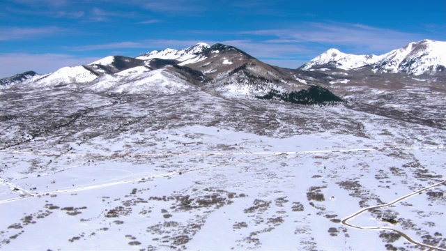 在蓝天的映衬下，雪花攀附在山坡和山峰上。视频素材