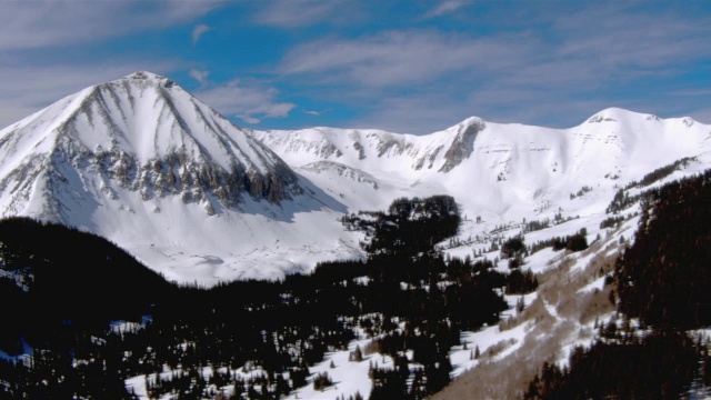 在蓝天的映衬下，雪花攀附在山坡和山峰上。视频素材
