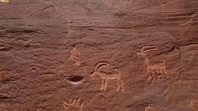 飞上墙壁接近岩石雕刻4k，无人机鸟瞰古代岩石雕刻拟人化的美洲土著和旧石器时代岩石雕刻。包括马，耶稣，十字架，权杖，外星人和人类的雕刻。位于犹他州和亚利桑那州边境视频素材