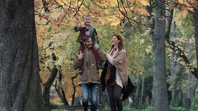好玩的家庭在公园里跑步，在秋天玩得很开心。视频素材