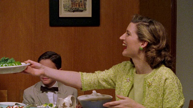 中镜头:一个小男孩把一碗明胶递给一个女人，然后女人在餐桌上把它递给他视频素材