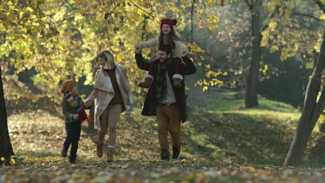 无忧无虑的家庭在公园里跑步，享受秋天的一天。视频素材