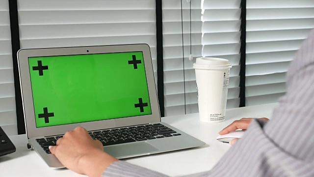 在办公室绿色屏幕的笔记本电脑上使用视频素材