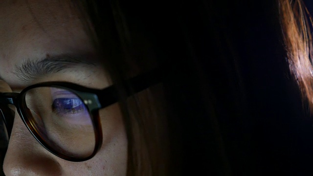 女人看着屏幕，反射在眼镜上视频素材