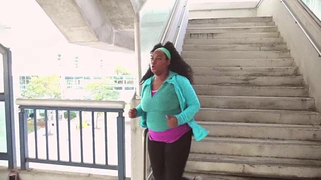 黑人妇女在城里锻炼，跑下楼梯视频素材