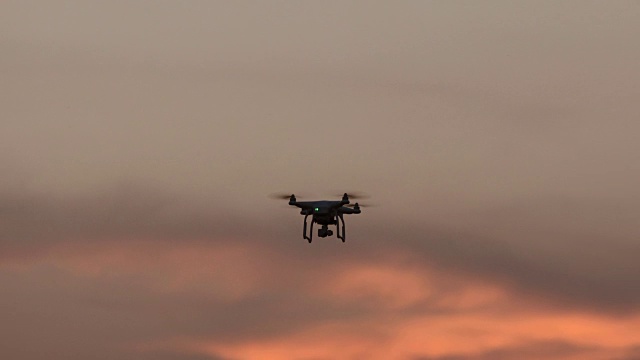 带数码相机的无人机四架直升机在日落上空盘旋视频下载