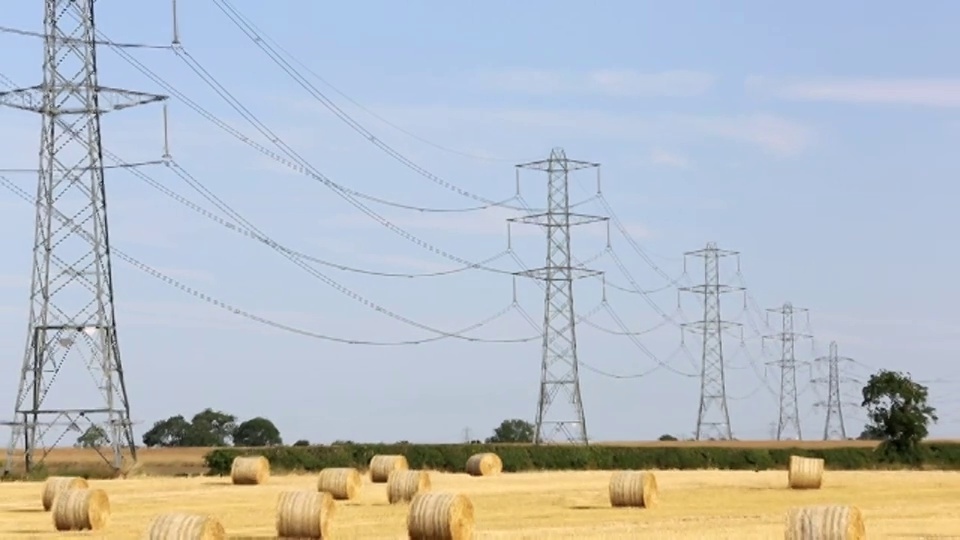 在英国约克郡的东海岸，麦田里的麦茬，与来自燃煤发电站的高压电线相连。视频下载