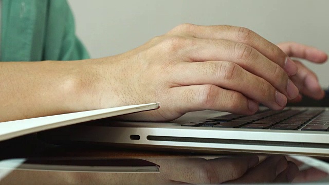 在家工作，用笔记本电脑写博客。咖啡店里男性的手在敲击键盘。视频素材