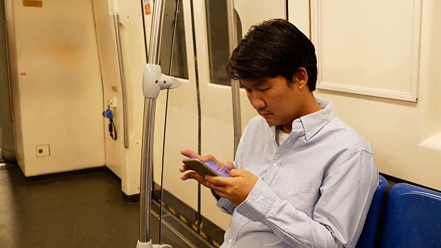 亚洲男人在地铁上用智能手机视频素材