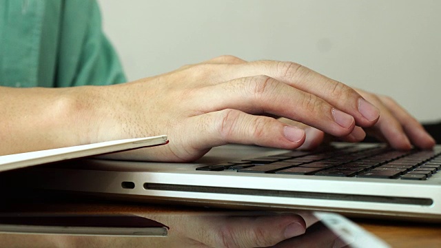 在家工作，用笔记本电脑写博客。咖啡店里男性的手在敲击键盘。视频素材