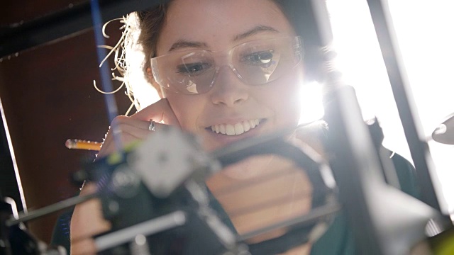 铜。在现代科技的工作场所，摄影架聚焦于富有创造力的女工程师检查3D打印机并做记录。视频素材