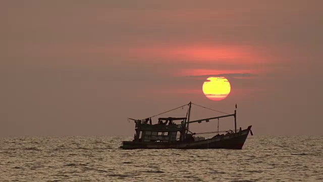 一艘渔船驶过夕阳下的海面视频下载