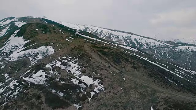山地车在雪山下攀登山脊的鸟瞰图视频素材
