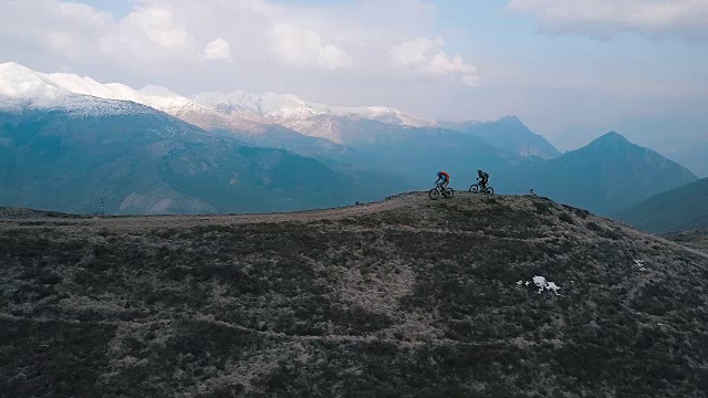 山地车在雪山下攀登山脊的鸟瞰图视频素材