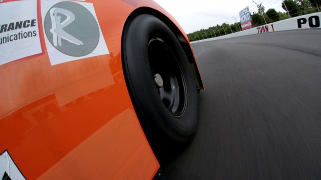 橙色的汽车司机在弯道上超过了红色的赛车，领先，在赛道上加速视频下载