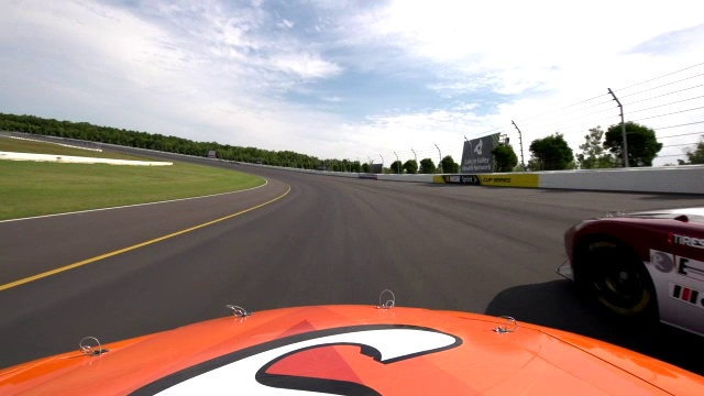 橙色的汽车司机在弯道上超过红色的赛车，取得领先，在赛道上加速。视频下载