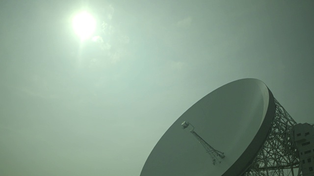 在英国柴郡乔瑞尔班克天文台的洛弗尔望远镜射电碟上，稀薄的云在明亮的太阳上缓慢移动。视频素材