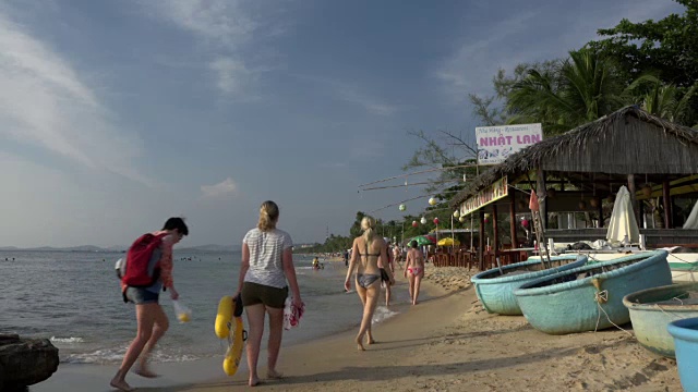 人们带着游艇和海滩餐厅沿着海滩散步视频下载
