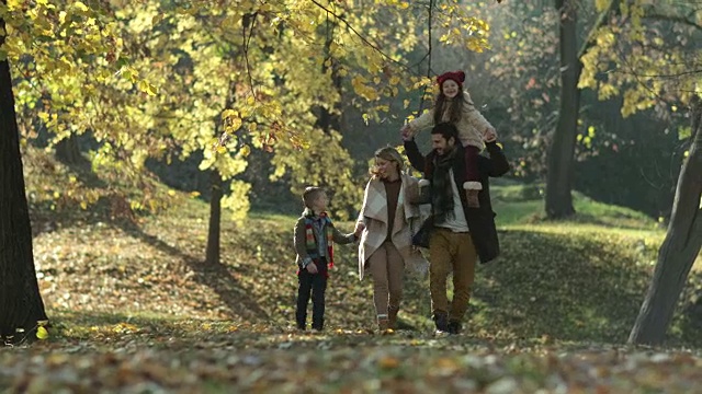 无忧无虑的家庭在大自然中奔跑，享受秋日的乐趣。视频素材