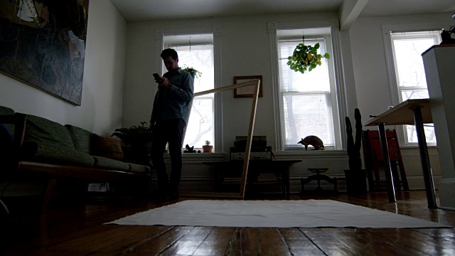 WS SLO MO。年轻的艺术家与智能手机站在铺画布的公寓地板上。视频素材