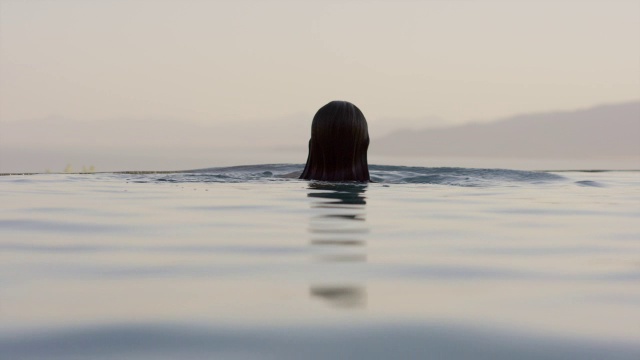 游泳女子观看日落在无限池/雪松山，犹他州，美国视频下载
