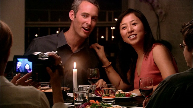 中镜头的女人拍摄夫妇在晚宴上与男人做鬼脸视频下载
