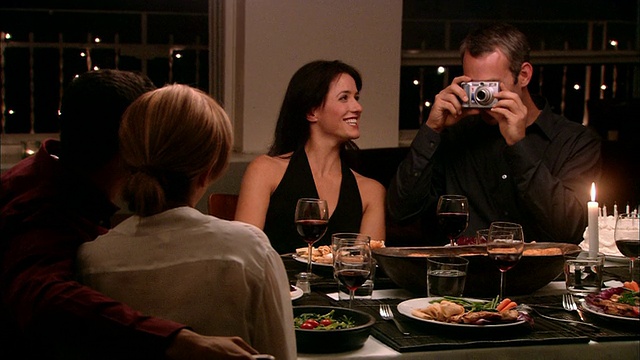 中景男子在晚宴上拍摄夫妇，其他女人在一旁观看视频下载