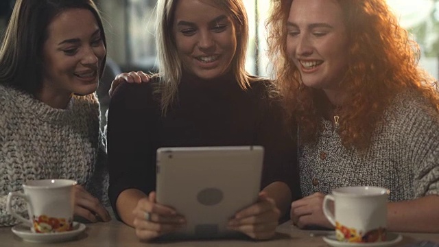 年轻快乐的女人在咖啡馆里用触控板笑着。视频素材