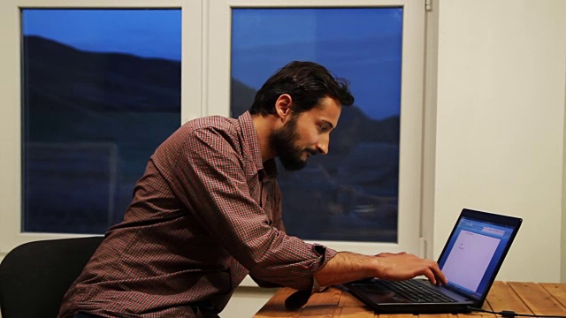 一名男子在一台笔记本电脑上工作，并将结果记录在窗户背景上视频下载