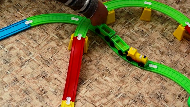 那个男孩在玩具铁路上推火车视频素材