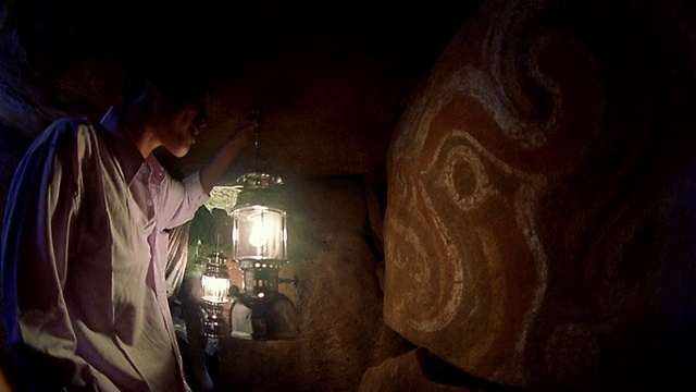 中景拍摄了两名男子提着灯笼进入洞穴并检查洞穴墙壁上的绘画/印度尼西亚巴令邦视频下载
