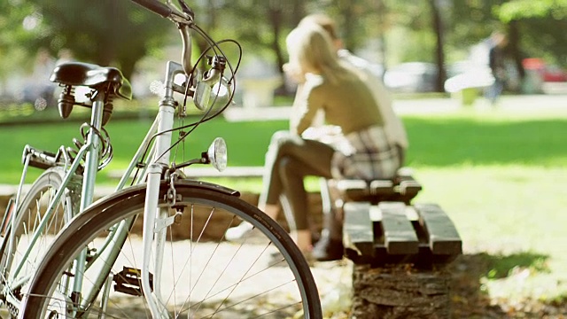 一对夫妇坐在长椅上停放的自行车旁视频素材