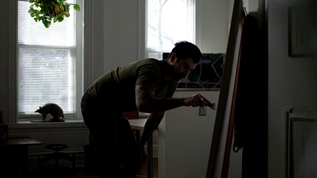 年轻的DIY艺术家WS SLO在公寓工作室用画笔在拉伸的画布上涂抹底漆。视频素材
